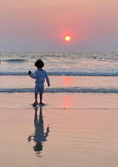 Barn vid havet i Indien med solnedgång